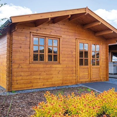 Hellbraunes Gartenhaus mit Bäume im Vordergrund